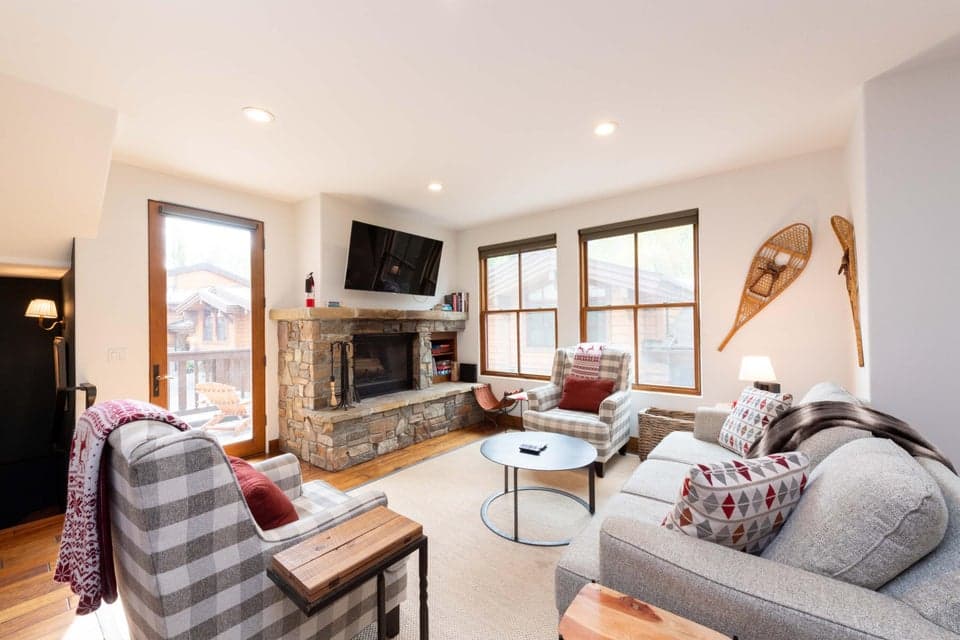Sun-Drenched Living Room with Mountain Views | Ketchum, ID. Featuring soaring high ceilings, rich wood flooring, and magnificent natural light, this expansive open-concept living area captures the essence of Sun Valley luxury just minutes from River Run Lodge.